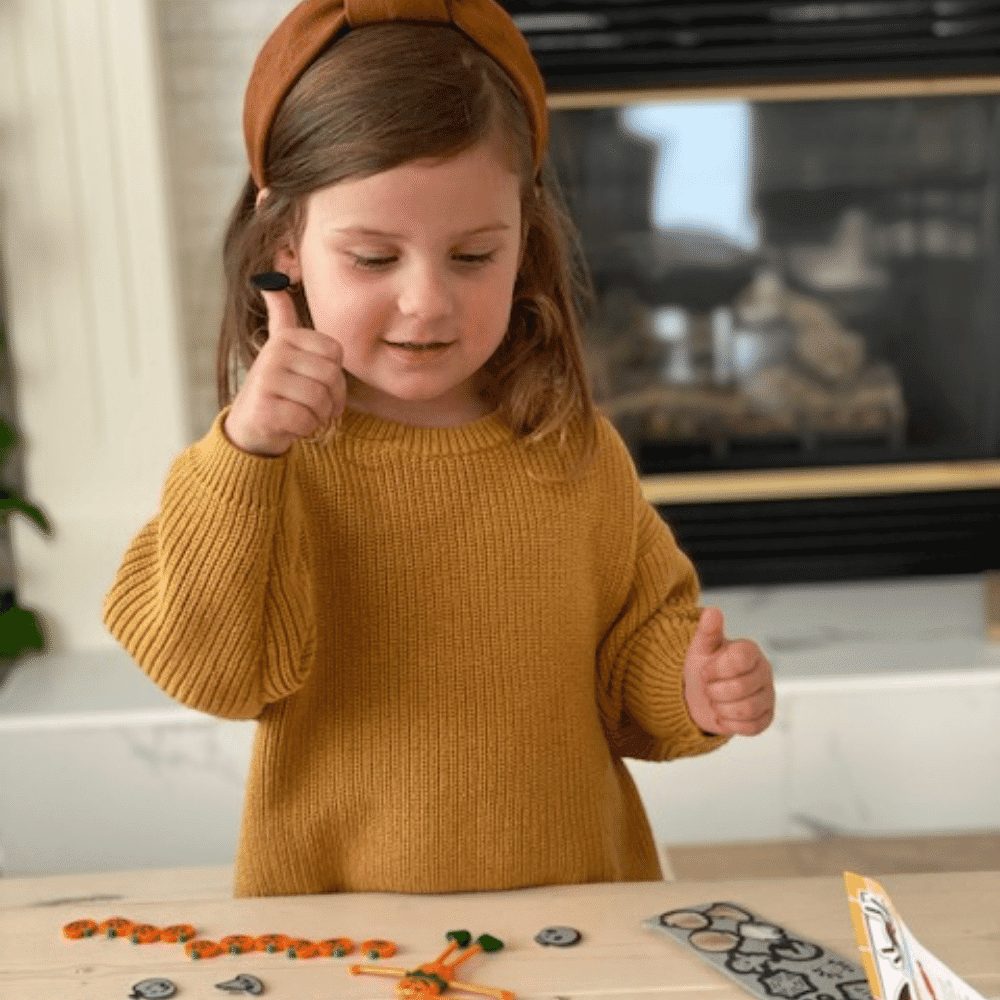 Kid crafting Halloween pumpkin decorations